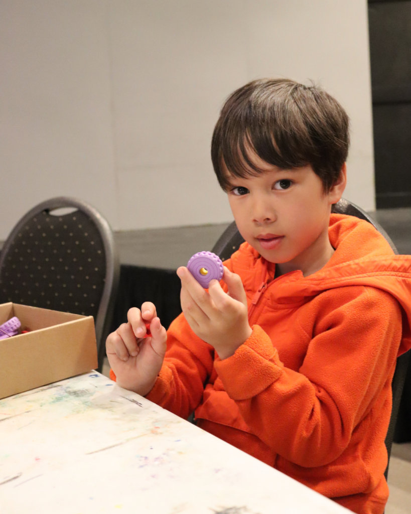 A kid holding a gear during one of our robotics program for kids.